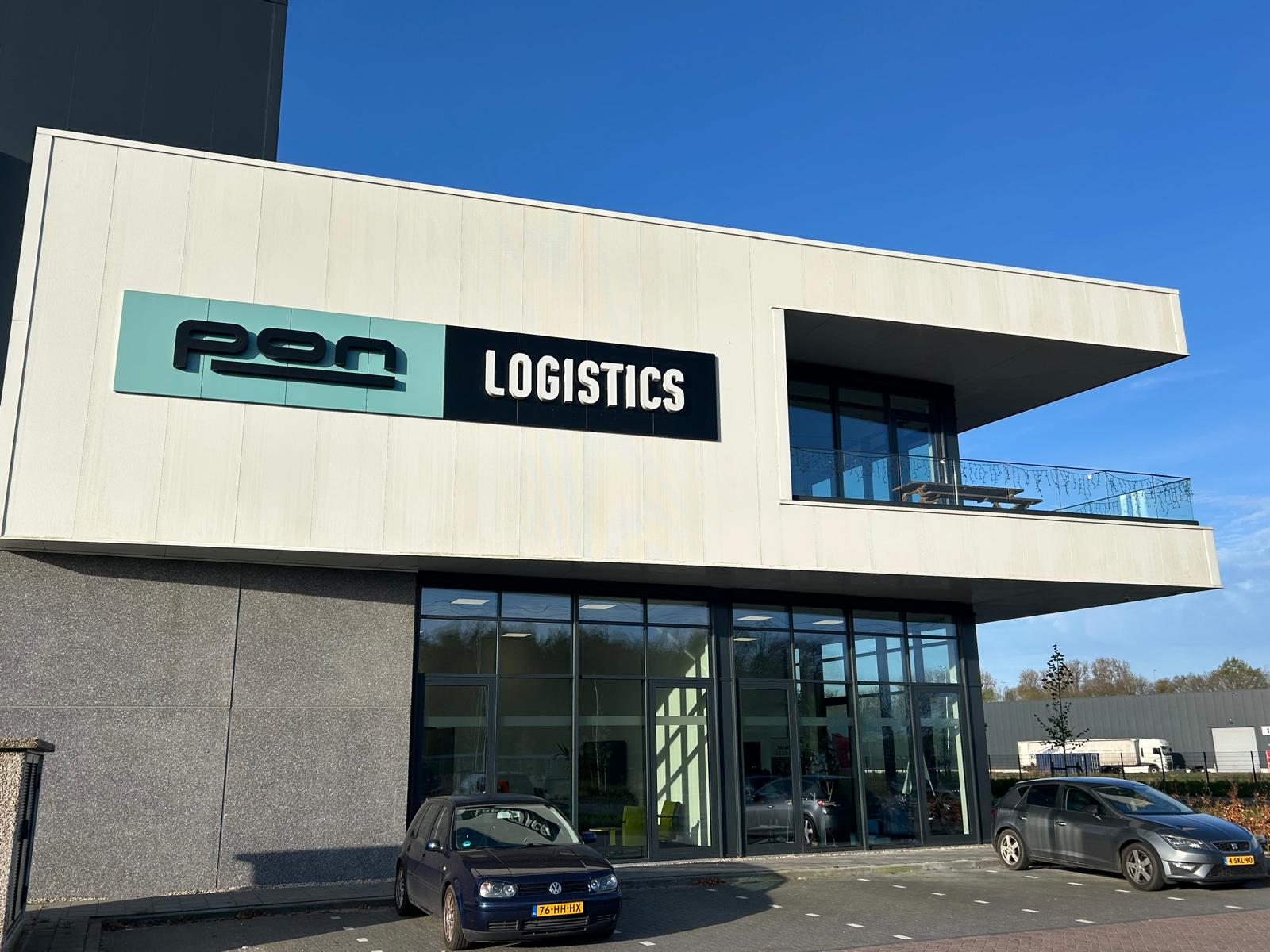Weißes modernes Gebäude mit PM Logistics Schild und zwei geparkten Autos davor
