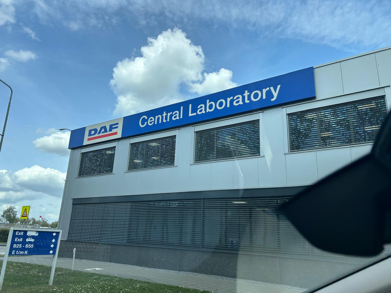 Ein modernes graues Gebäude mit blauer Central Laboratory Beschilderung und weißen Wolken