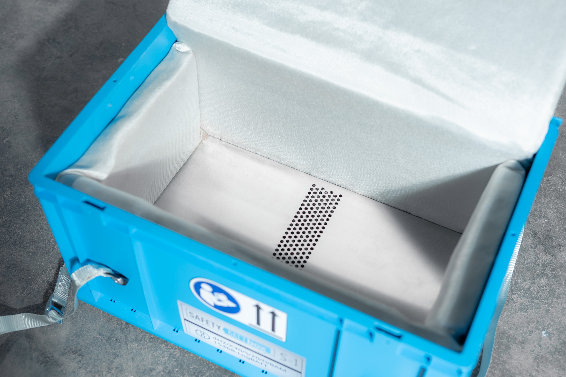 Offene blaue SafetyBATTbox S-1 mit weißer Isolierung und gelochtem Metallboden, leer