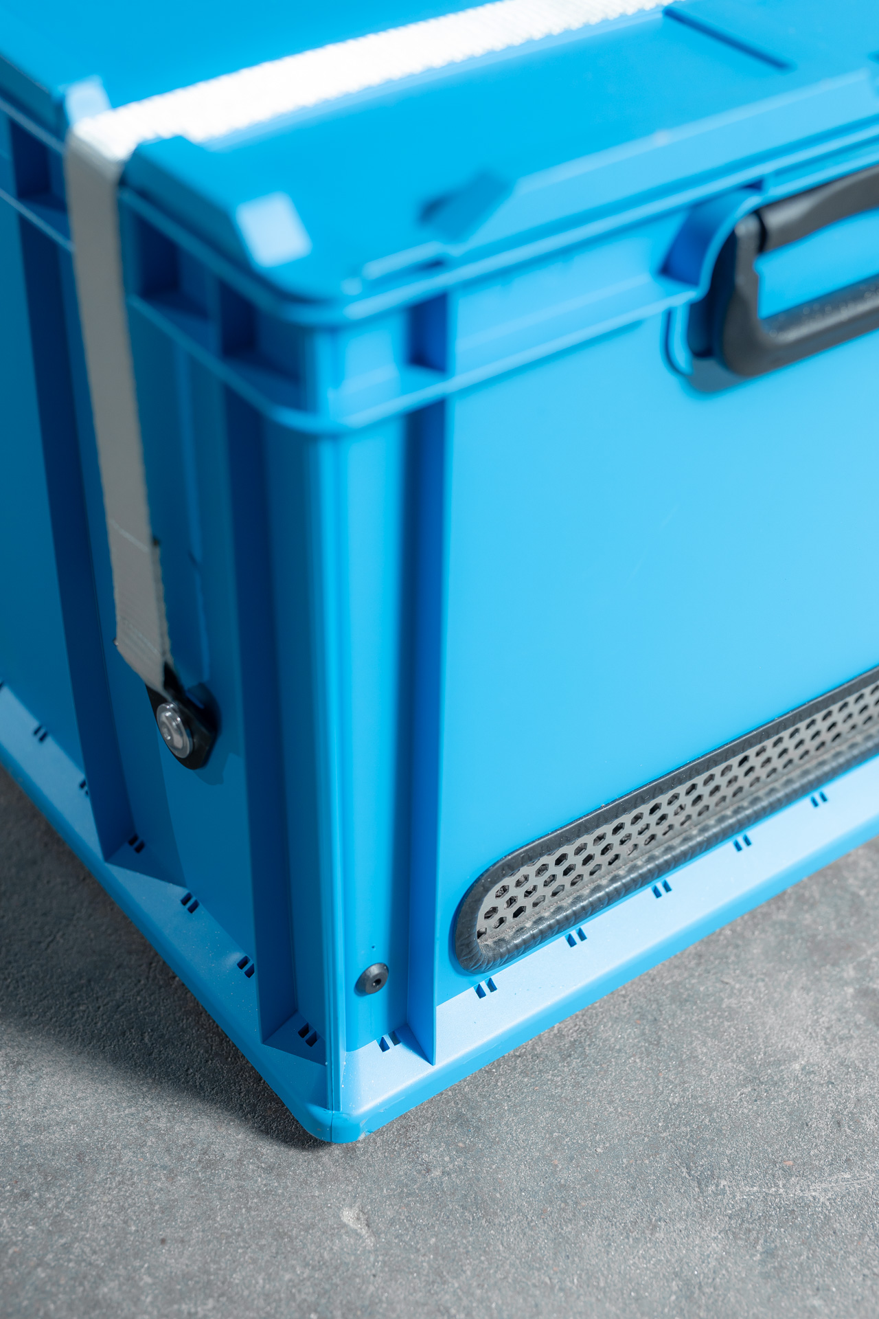 Blaue Transportkiste ohne Person mit Griff und Lüftungsgitter, neutraler Eindruck