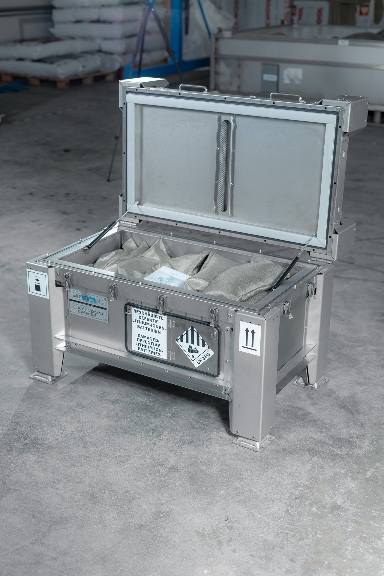 Offene graue Metallkiste SafetyBATTbox M-2 ohne Personen mit Warnsymbol und Polstereinlage
